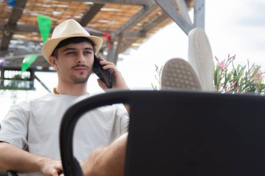 Plaj barında cep telefonuyla konuşan rahat genç bir adam.