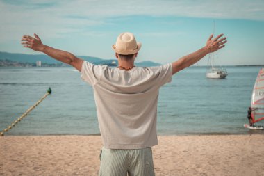 Sahilde kollarını açmış bekleyen bir adam.