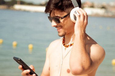 Kumsalda akıllı telefon kullanan genç bir adam.