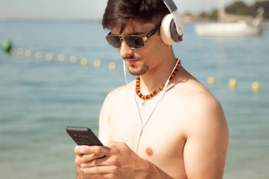 Kumsalda akıllı telefon kullanan genç bir adam.