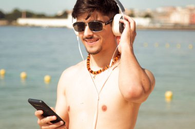 Kumsalda akıllı telefon kullanan genç bir adam.