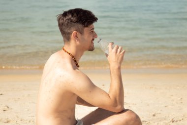 yakışıklı genç bir adam sahilde içme suyu