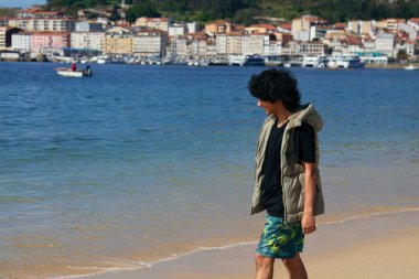 Genç adam sahilde yürüyor.