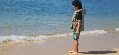 Genç adam sahilde yürüyor.