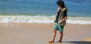 Genç adam sahilde yürüyor.