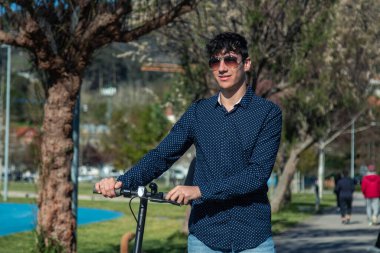 Sokakta elektrikli scooter kullanan genç bir adam.