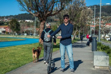 Sokakta elektrikli scooter kullanan genç adam.