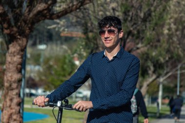 Sokakta elektrikli scooter kullanan genç bir adam.