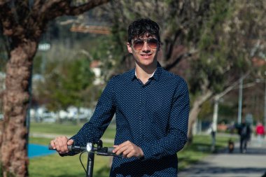 Sokakta elektrikli scooter kullanan genç adam.