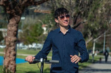 Sokakta elektrikli scooter kullanan genç adam.