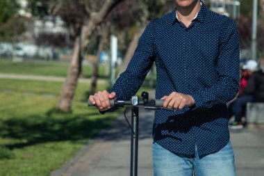 Sokakta elektrikli scooter kullanan genç adam.