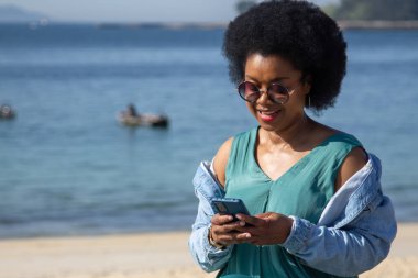 Plaj geçmişi olan genç bir kadın telefonundan mesajlarını okuyor.