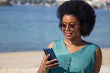 Plaj geçmişi olan genç bir kadın telefonundan mesajlarını okuyor.