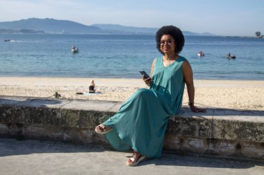 Sahilde cep telefonu kullanan genç bir kadın.