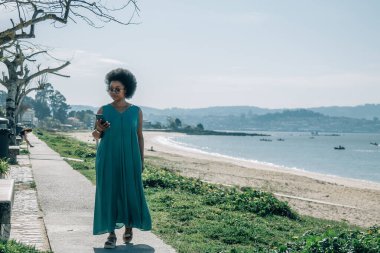 Sahilde cep telefonu kullanan genç bir kadın.