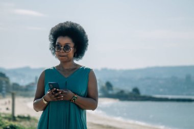 Sahilde cep telefonu kullanan genç bir kadın.