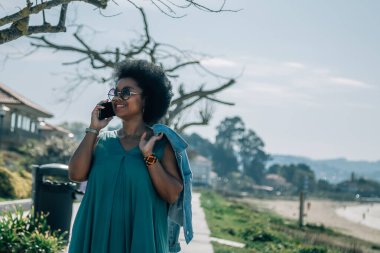 Kumsalda cep telefonuyla konuşan genç bir kadın.