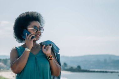 Kumsalda cep telefonuyla konuşan genç bir kadın.