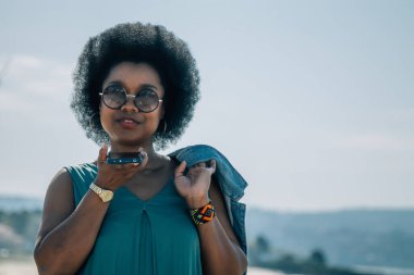 Genç bir kadın dışarıda cep telefonuyla mesaj ya da ses gönderiyor.