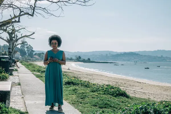 Sahilde cep telefonu kullanan genç bir kadın.