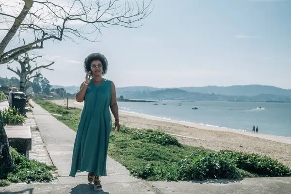 Kumsalda cep telefonuyla konuşan genç bir kadın.