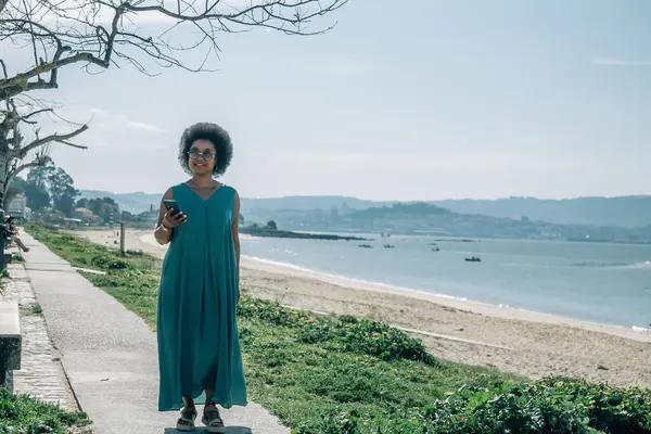 Sahilde cep telefonu kullanan genç bir kadın.