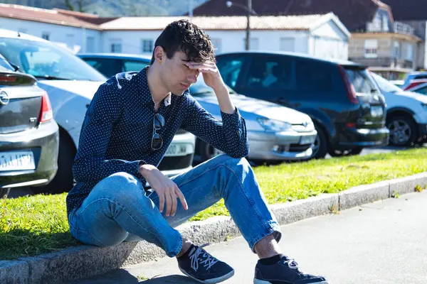 Genç çocuk bunalmış ve sokakta tek başına oturuyor.