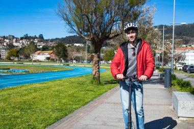 Sokakta elektrikli scooter kullanan genç adam.