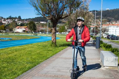 Sokakta elektrikli scooter kullanan genç adam.