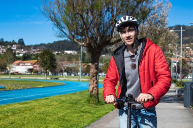 Sokakta elektrikli scooter kullanan genç adam.