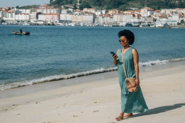 Sahildeki Afrikalı kadın akıllı telefondan mesaj okuyor., 