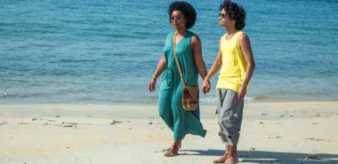 Sahilde el ele yürüyen çok ırklı bir çift.