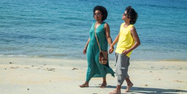 Birbirine aşık çiftler kumsalda el ele yürüyorlar.