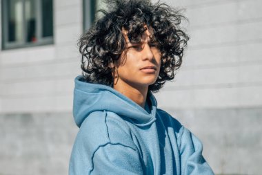 Sokakta kollarını kavuşturmuş genç Latin bir adam.