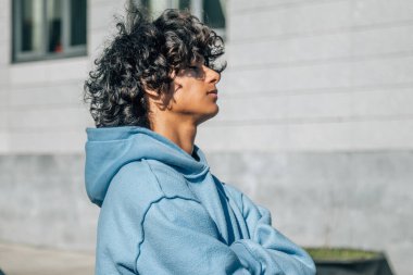 Sokakta kollarını kavuşturmuş genç Latin bir adam.