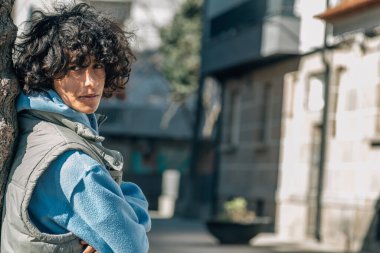 Sokakta kollarını kavuşturmuş genç Latin bir adam.