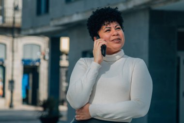 Sokakta cep telefonuyla konuşan orta yaşlı bir kadın.