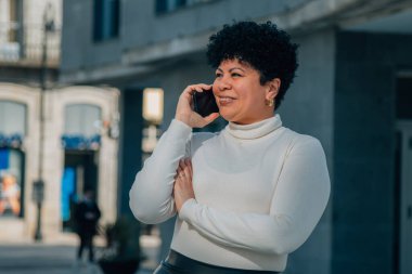 Sokakta cep telefonuyla konuşan orta yaşlı bir kadın.