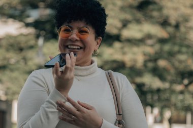 Orta yaşlı bir kadın akıllı telefonuyla sesli ya da sesli mesaj gönderiyor.