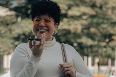 Orta yaşlı bir kadın akıllı telefonuyla sesli ya da sesli mesaj gönderiyor.