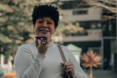 Orta yaşlı bir kadın akıllı telefonuyla sesli ya da sesli mesaj gönderiyor.