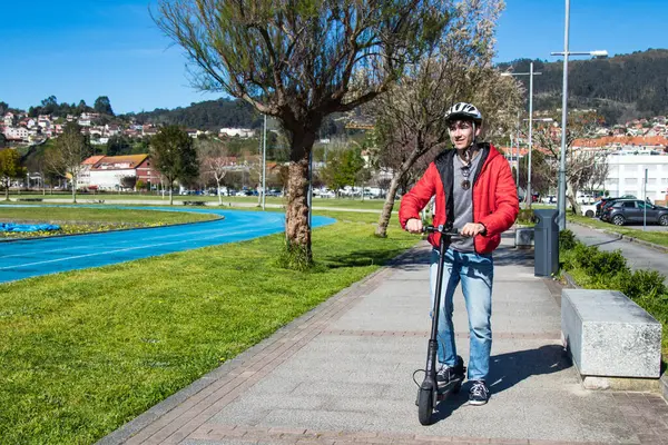 Sokakta elektrikli scooter kullanan genç adam.