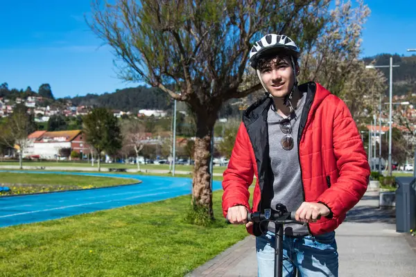 Sokakta elektrikli scooter kullanan genç adam.