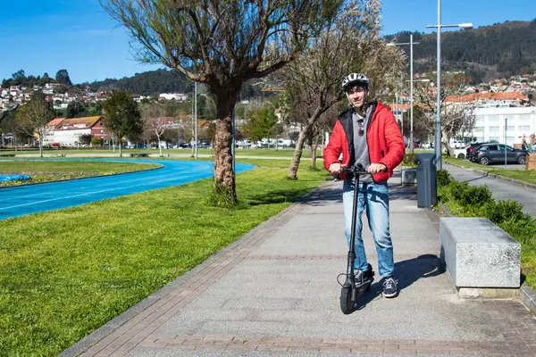 Sokakta elektrikli scooter kullanan genç adam.
