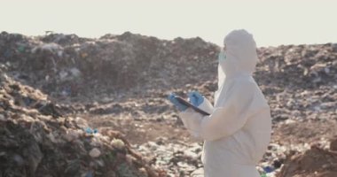 Koruyucu maskeli bir adam bir bitki üzerinde çalışıyor..