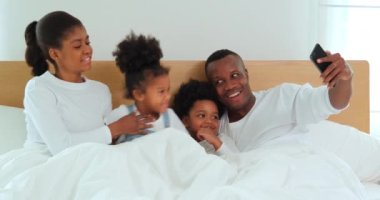 Aile, eğlence, çocukluk, aile evde yatakta selfie çekmek.