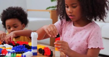 Afro-Amerikalı çocuklar evde oturmuş resim çiziyorlar.