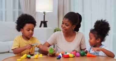 Annesi evde oyuncaklarla oynayan Afrikalı Amerikalı çocuklar.