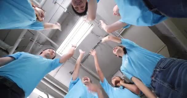 チームスピリットをサポートするブルーのTシャツを着たボランティアが手を合わせ — ストック動画