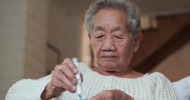 Evde glukometre kullanan yaşlı bir kadın.